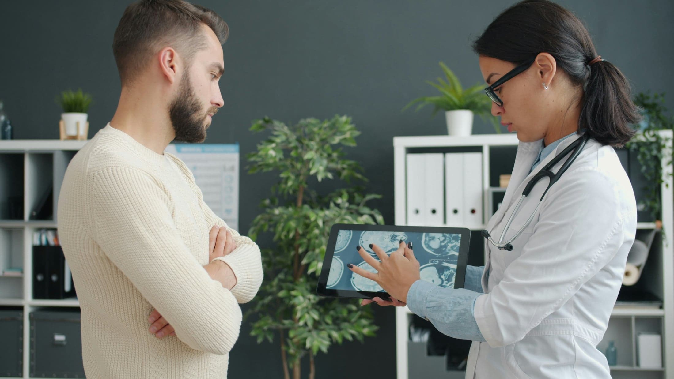 Physician reviewing diagnostic scans on a tablet with a patient